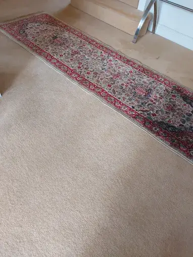 Long patterned runner rug laid on a carpeted floor